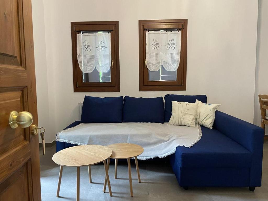 un canapé bleu avec une table et deux fenêtres dans l'établissement Pelion Bloom, à Zagora