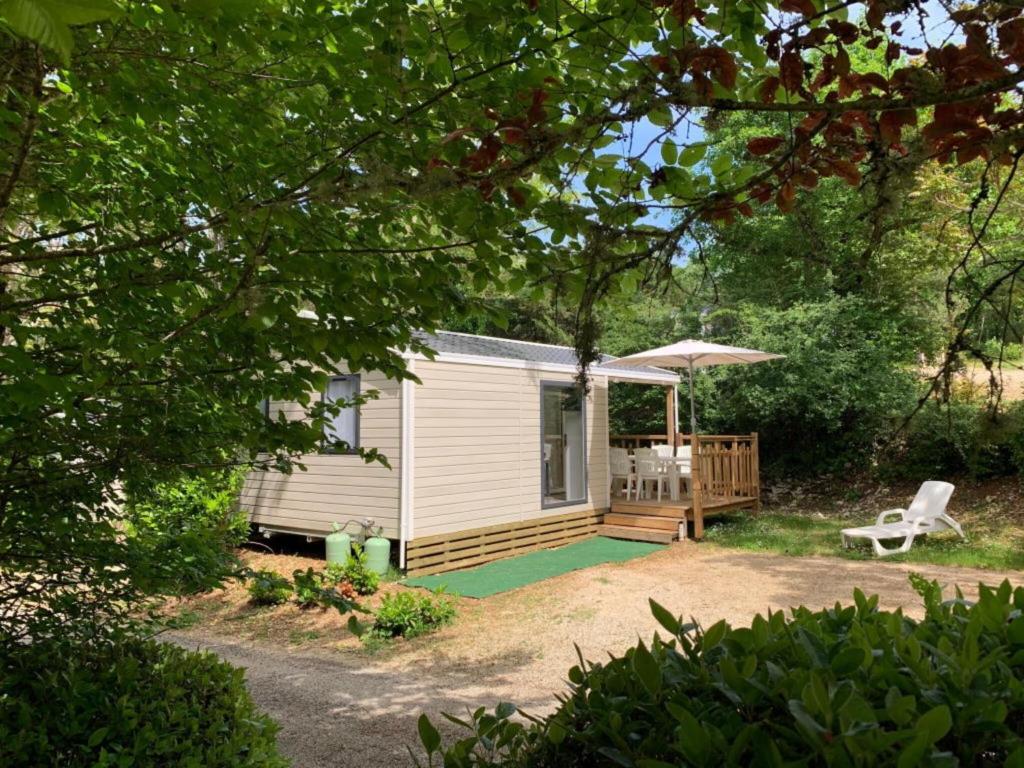 eine Hütte mit einer Terrasse, einem Stuhl und einem Sonnenschirm in der Unterkunft Mobilhome Malaga Climatisé 31 in Saint-Martial-de-Nabirat