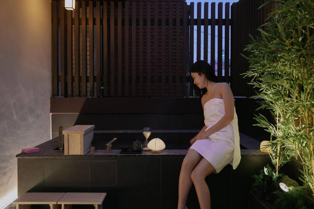 una mujer con un vestido blanco sentada en un banco en Stay Passport Nagoya Ryokan Anyang Pyeongchon, en Anyang