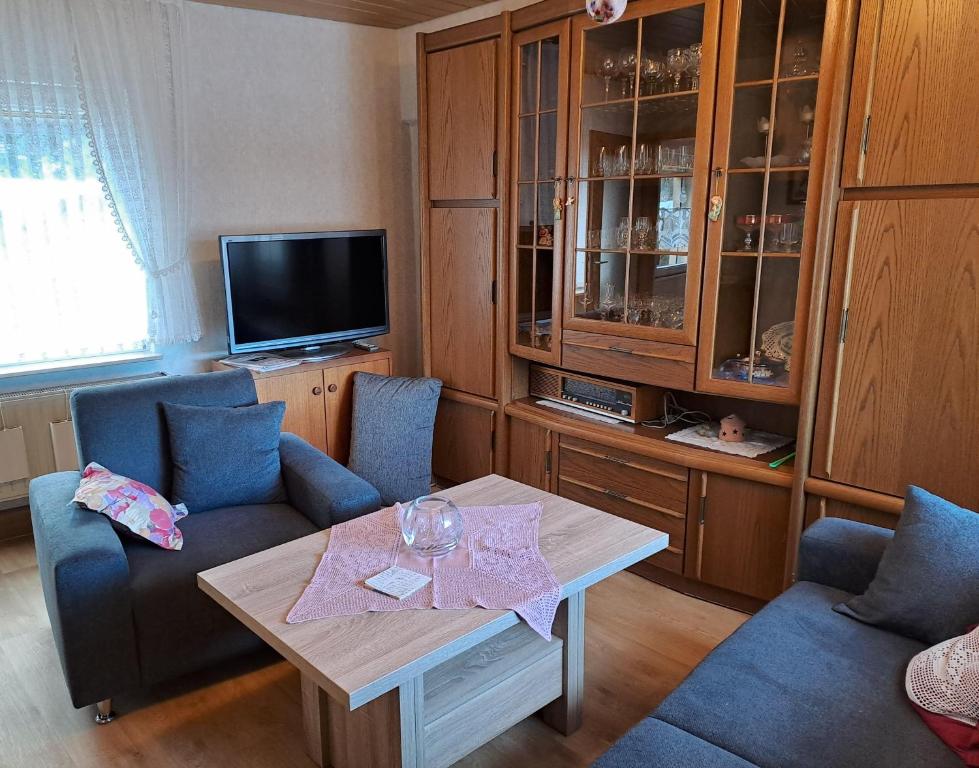 un salon avec une table, des chaises et une télévision dans l'établissement An-der-Stadtmauer, à Fladungen