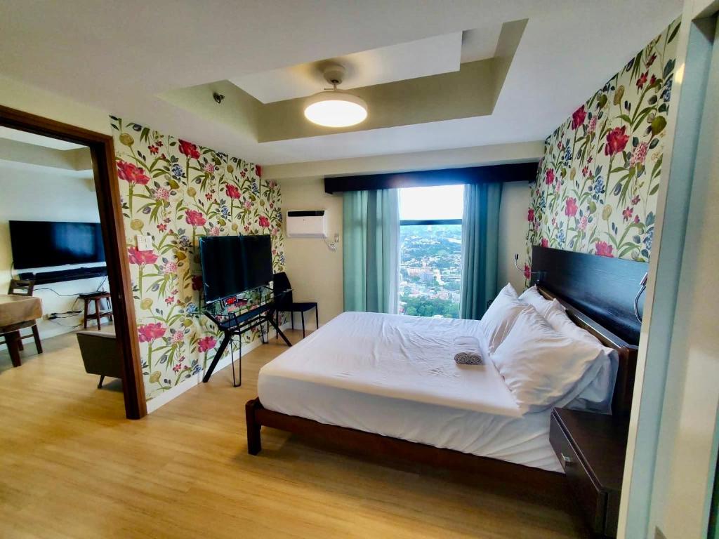 une chambre avec un grand lit avec des fleurs sur le mur dans l'établissement 1bedroom suite 50th floor with balcony and bathtub at Horizons 101 tower 1, à Cebu