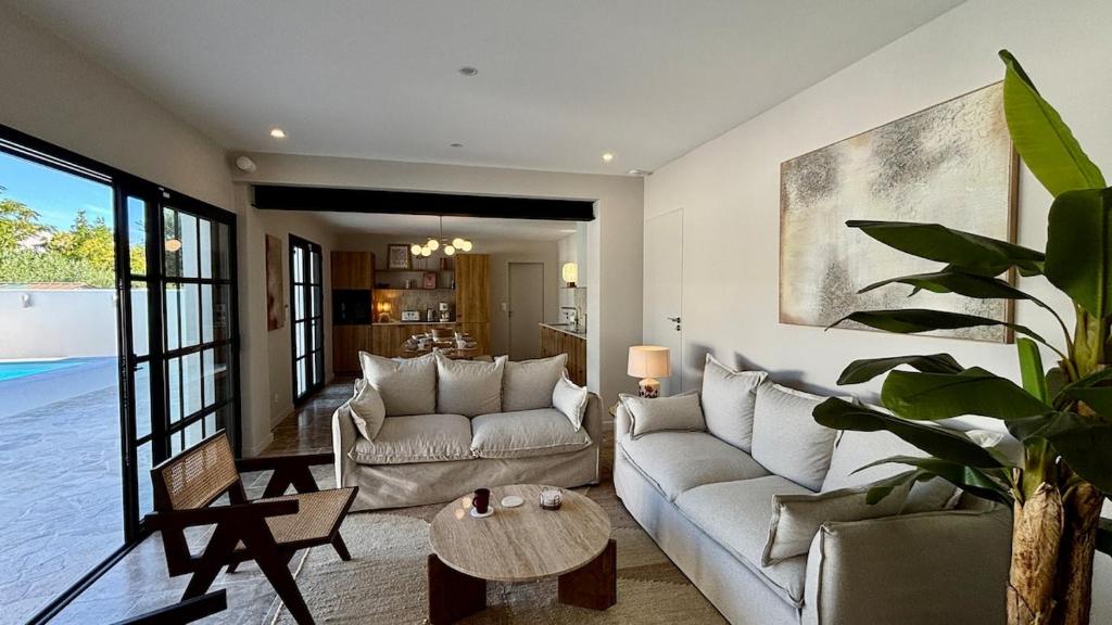 uma sala de estar com um sofá e uma mesa em Villa premium, tribu friendly, vaste patio & piscine em Mauguio