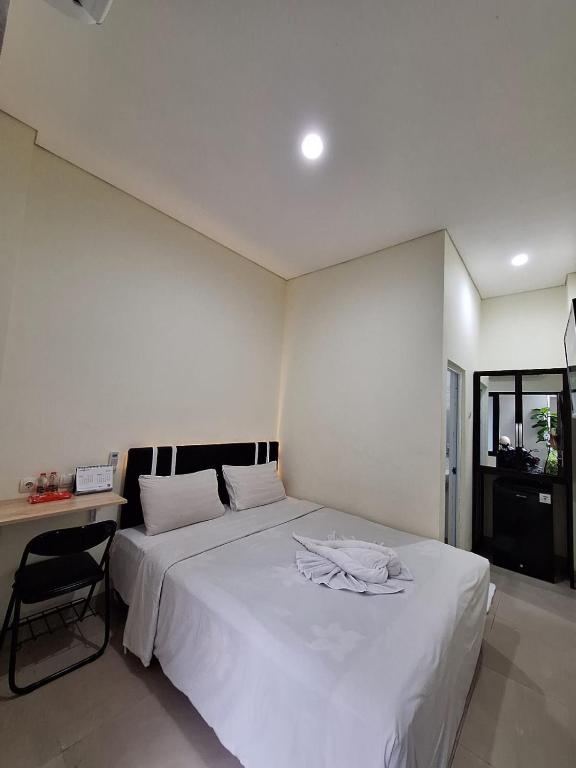 a bedroom with a large white bed and a desk at TRAM - The Seturan Raya Eksklusif Rooms in Yogyakarta