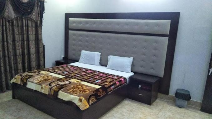 Hotel Comfy Lodge في Dargai: غرفة نوم مع سرير مع اللوح الأمامي كبير