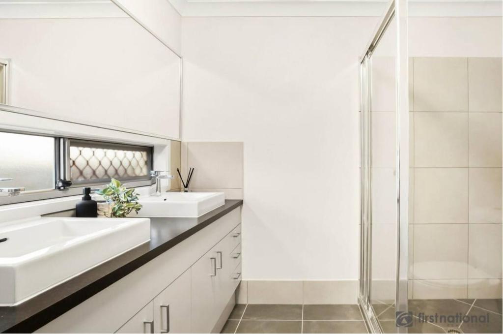 ein Badezimmer mit zwei Waschbecken und einer Dusche in der Unterkunft Bright Family Retreat - Quiet Caboolture Stay in Caboolture