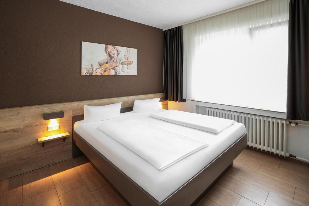 a large bed in a room with a large window at Hotel Frohnhauser Hof in Essen