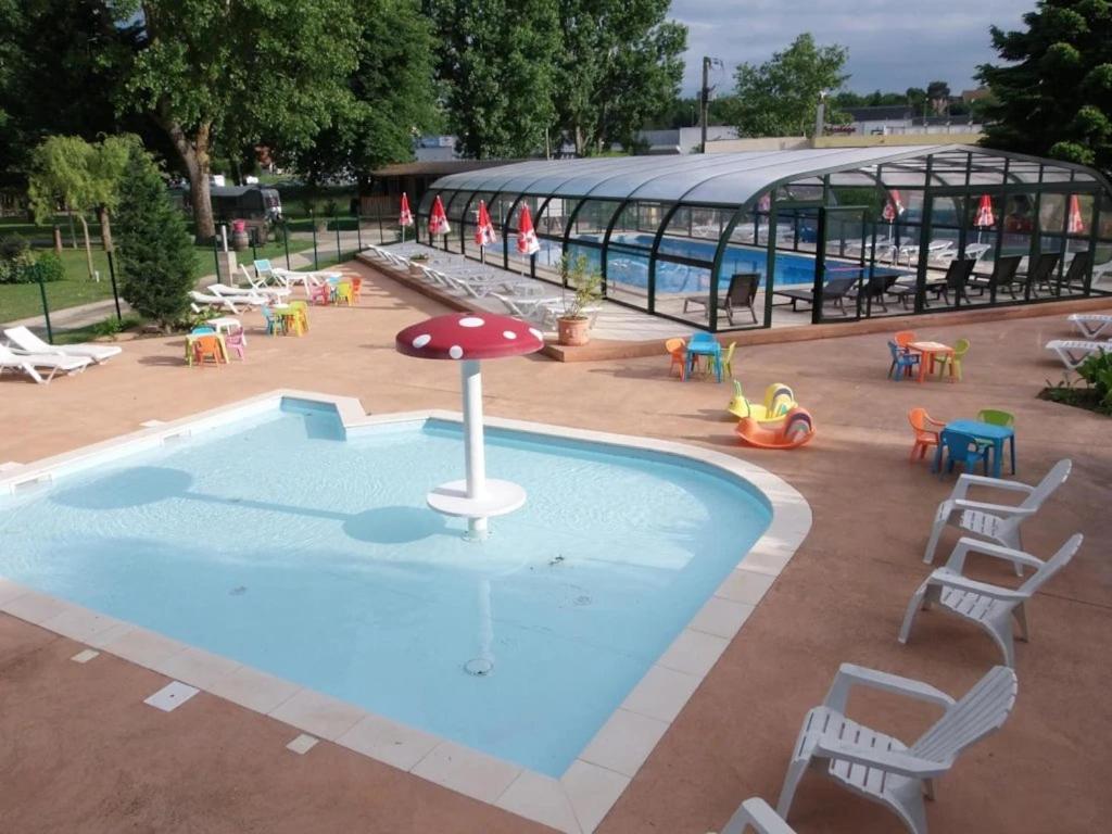 a pool with a playground with chairs and a umbrella at ZEcamping 4 étoiles dog friendly bar piscine couverte in Faverolles-sur-Cher