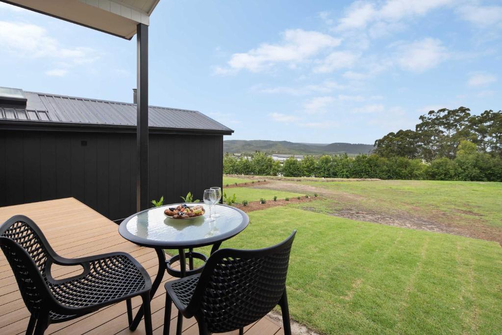 a patio with a table and chairs on a deck at Lemon Myrtle Villa in Valdora