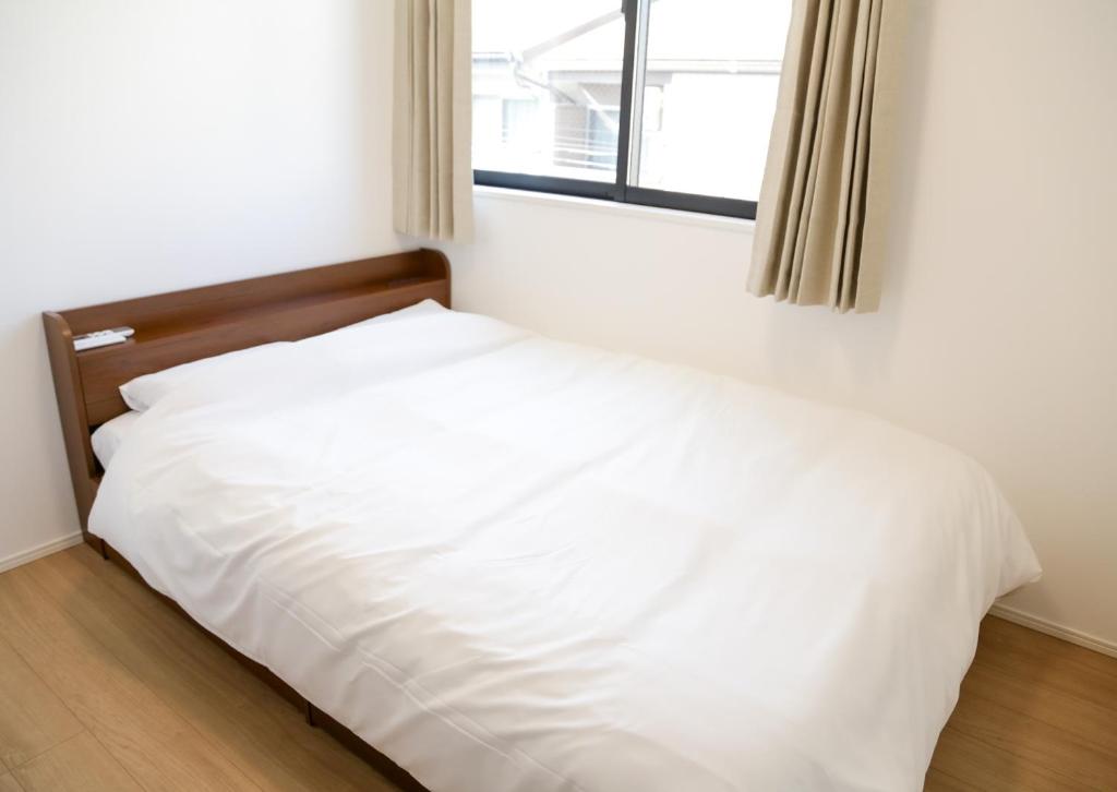 uma cama branca em um quarto com janela em 福岡旅路 博多住吉包棟民宿 3號館 em Fukuoka