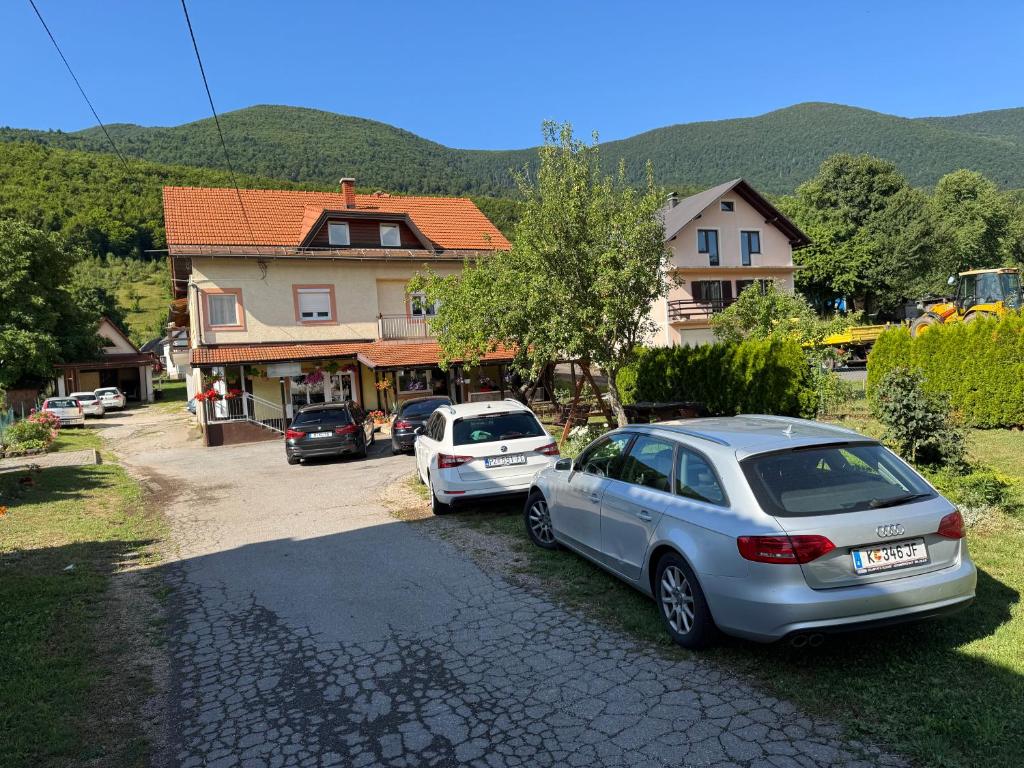 two cars parked in front of a house at Apartmani Ruza in Krasno Polje
