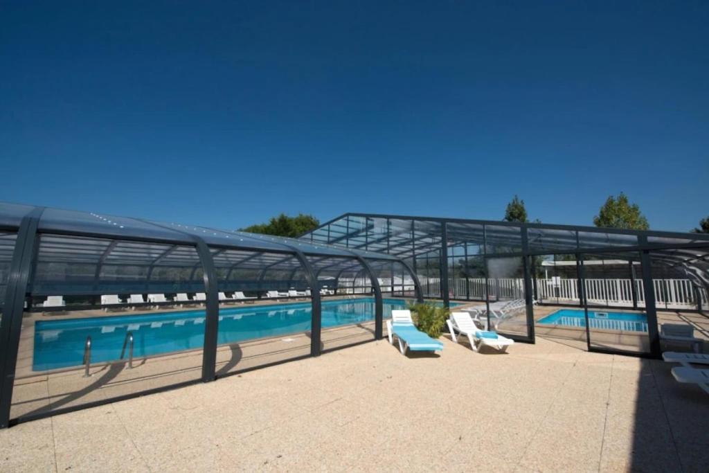 a swimming pool with two lounge chairs next to it at ZEcamping 3 étoiles familial animaux acceptés piscine couverte et chauffée in Saint-Hilaire-de-Talmont