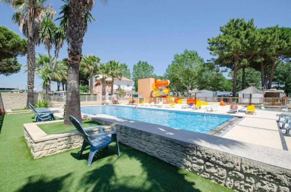 a swimming pool with a blue chair next to a wall at Camping 4 étoiles - Piscine - ccbbecd in Le Grau-dʼAgde
