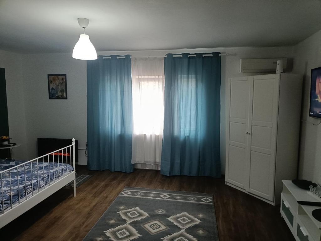 een slaapkamer met blauwe gordijnen en een wieg bij Apartament terasa in Boekarest