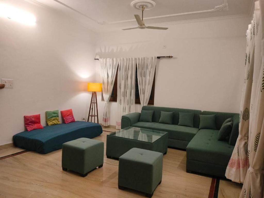 德拉敦Ashiana By Ijabojyu的客厅配有绿色沙发和搁脚凳