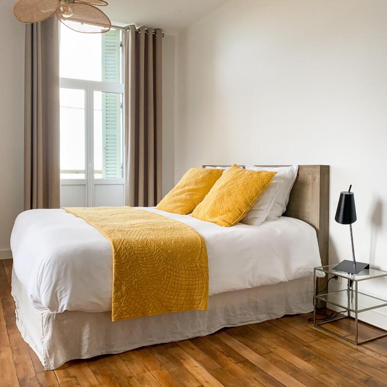 a bedroom with a white bed with yellow blankets and a window at La Cour Tellier in Rilly-la-Montagne
