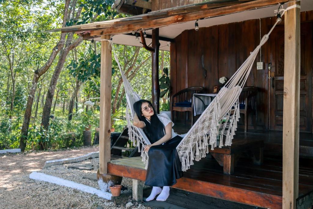 a woman sitting in a hammock in a cabin at Baanlamun in Ban Dong Bang