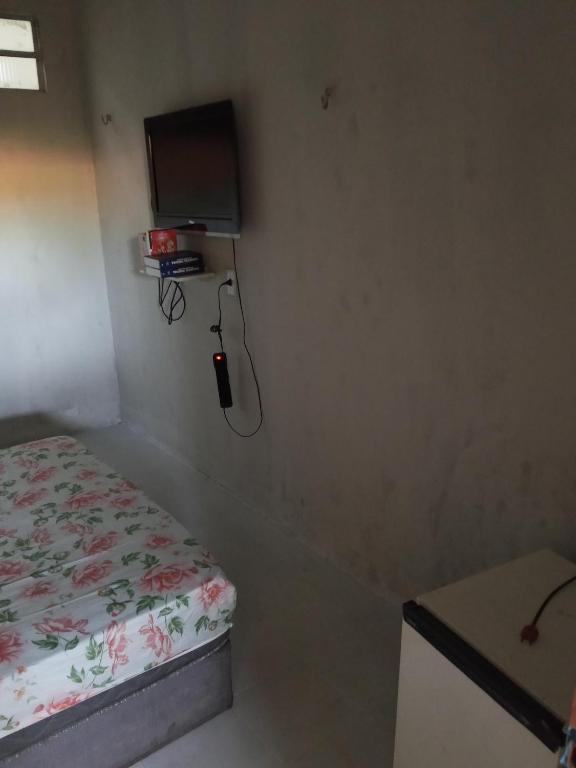 a small room with a bed and a tv on the wall at Quarto e banheiro in Camocim