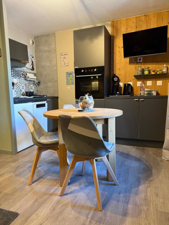 eine Küche mit einem Holztisch und zwei Stühlen in der Unterkunft Logement cosy à la montagne in Bourg-Saint-Maurice