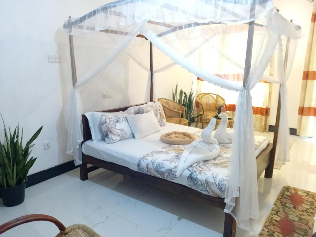 a bedroom with a white canopy bed with two people on it at Tamasha Mango House in Dickwella