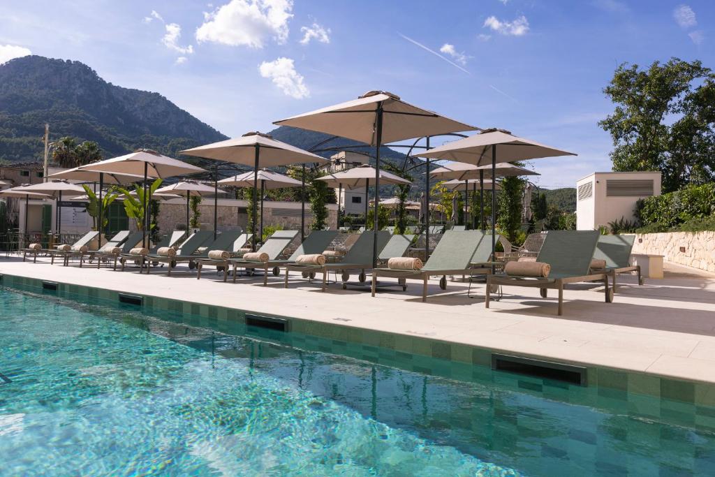 a group of chairs and umbrellas next to a swimming pool at Alcázar Hotel Sóller in Sóller