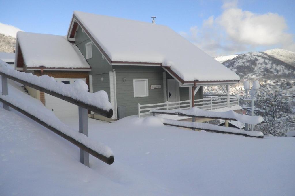 une maison couverte de neige avec des montagnes en arrière-plan dans l'établissement Le Chalet Vert entre nature et animations, à La Bresse