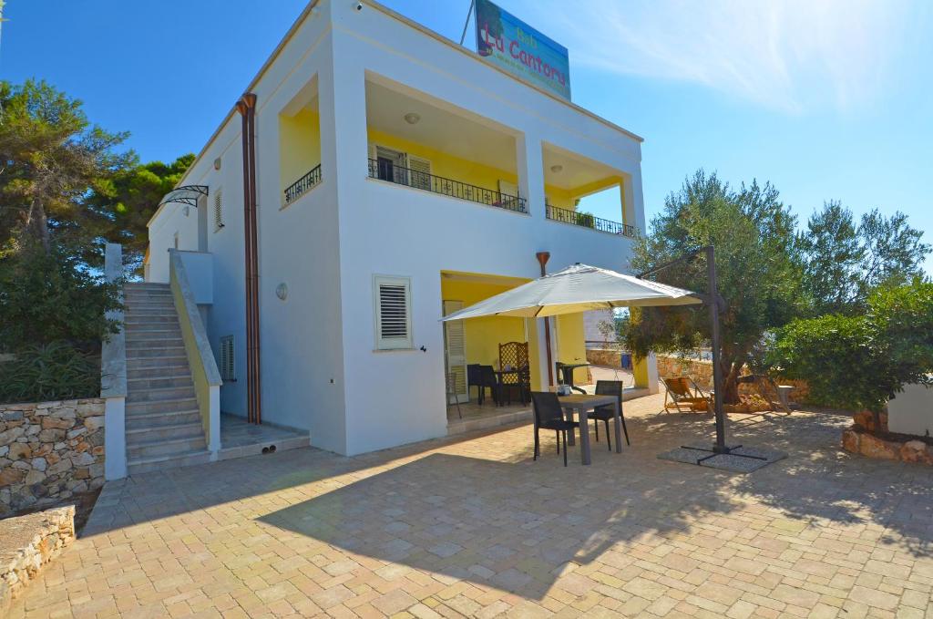 a white building with a table and an umbrella at B&B Lu Cantoru in Marina di Pescoluse