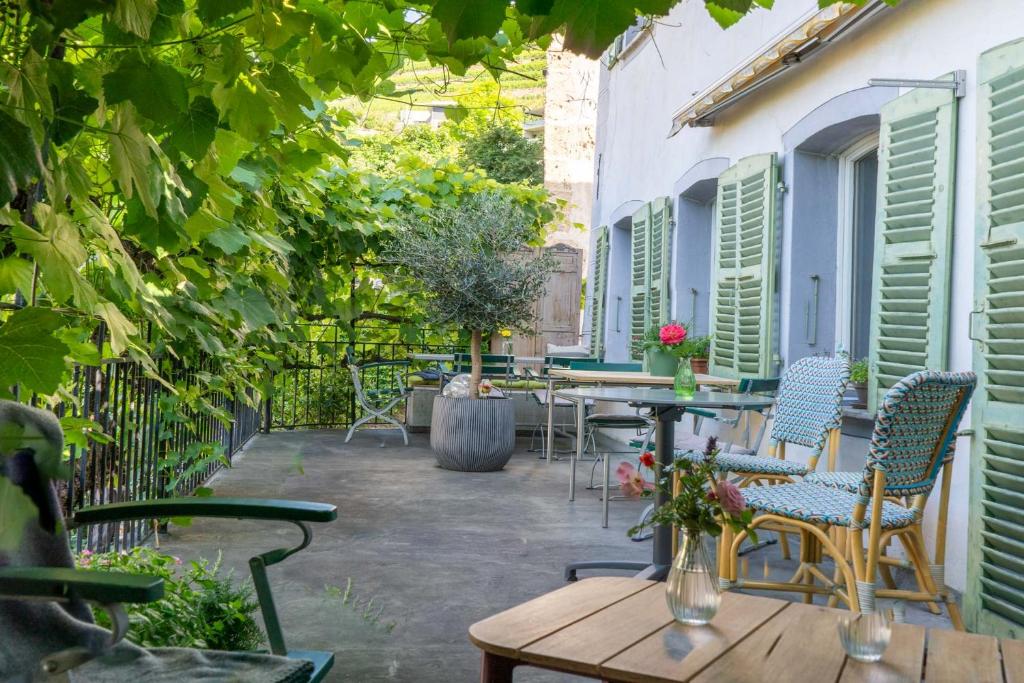 an outdoor patio with tables and chairs and trees at BnB Feuille de Vigne in Saint-Léonard