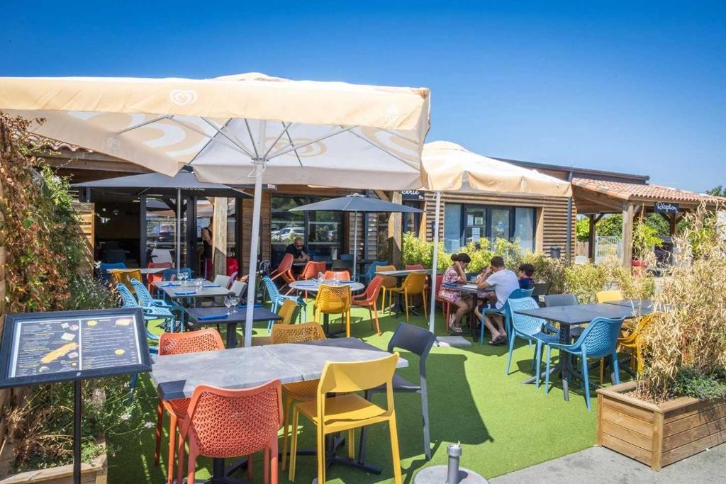 un restaurant avec des tables et des chaises avec des gens assis dessus dans l'établissement Camping 4 étoiles - Parc aquatique - eeiaia, à Olonne-sur-Mer