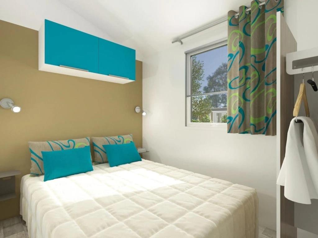 une chambre avec un lit avec des oreillers bleus et une fenêtre dans l'établissement Camping 4 étoiles - Piscine - ccaaeah, à La Baule