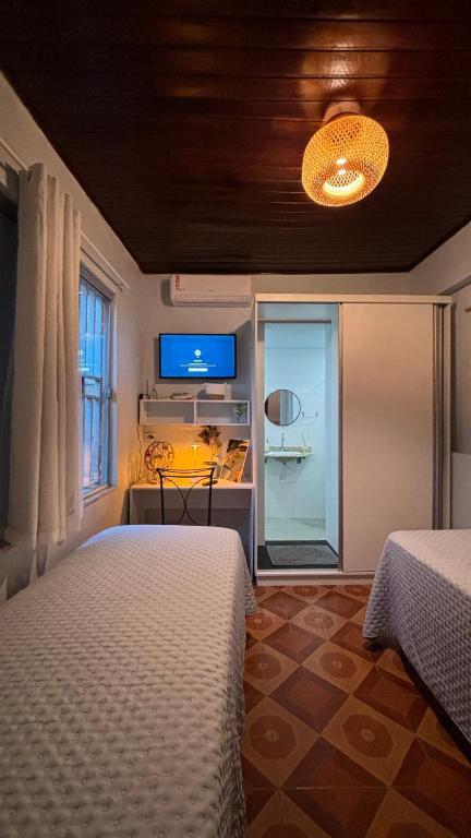 a bedroom with two beds and a desk and a television at Casa Janela Azul in Belém