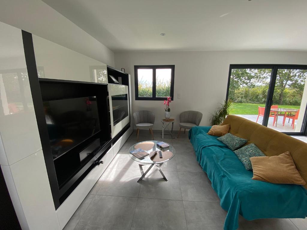 a living room with a blue couch and a flat screen tv at Le gîte des Acacias in Montech