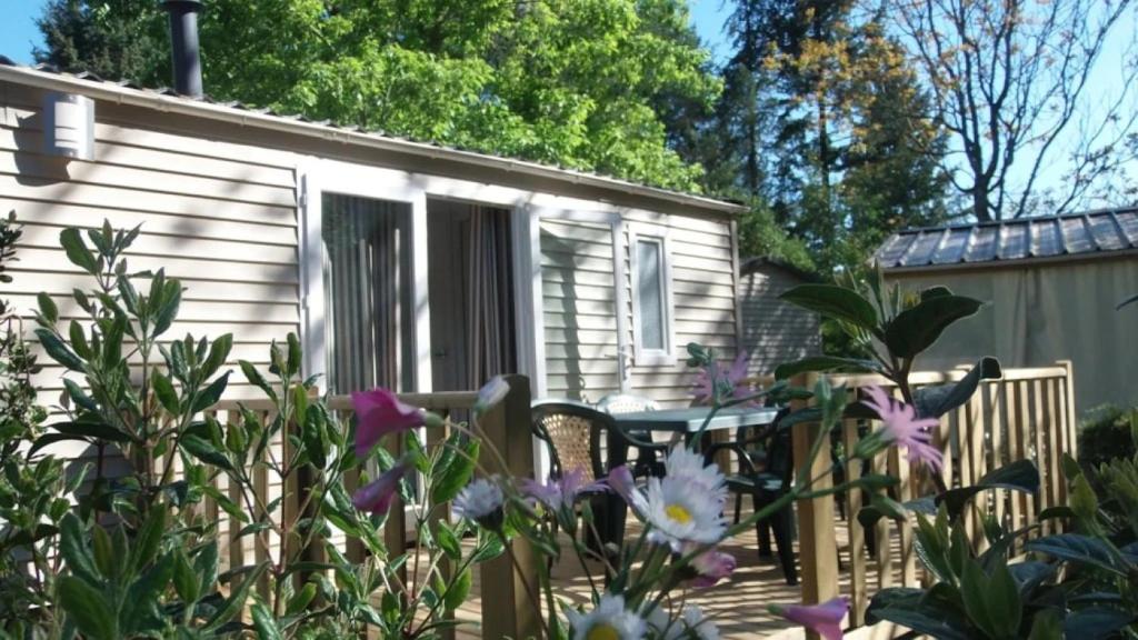 ein Wohnwagen mit Tisch und Stühlen in einem Garten in der Unterkunft Chalet 3 étoiles - Piscine - ccaibfi in Saint-Jean-du-Gard