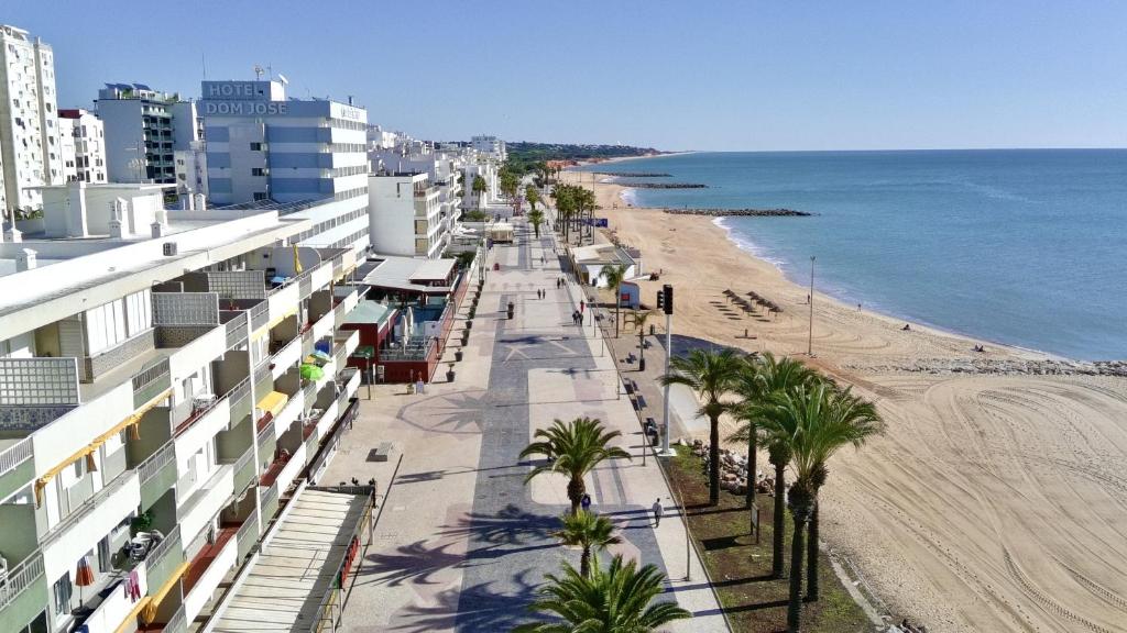 vista su una spiaggia con edifici e palme di Quarteira Central 3 by Homing a Cavacos