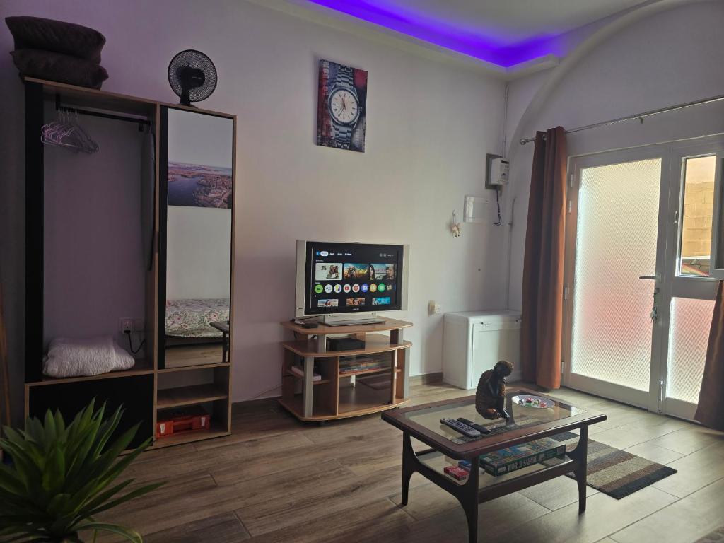 Una sala de estar con un televisor y una mesa. en Studio Groundfloor Apartment, en Il-Gżira
