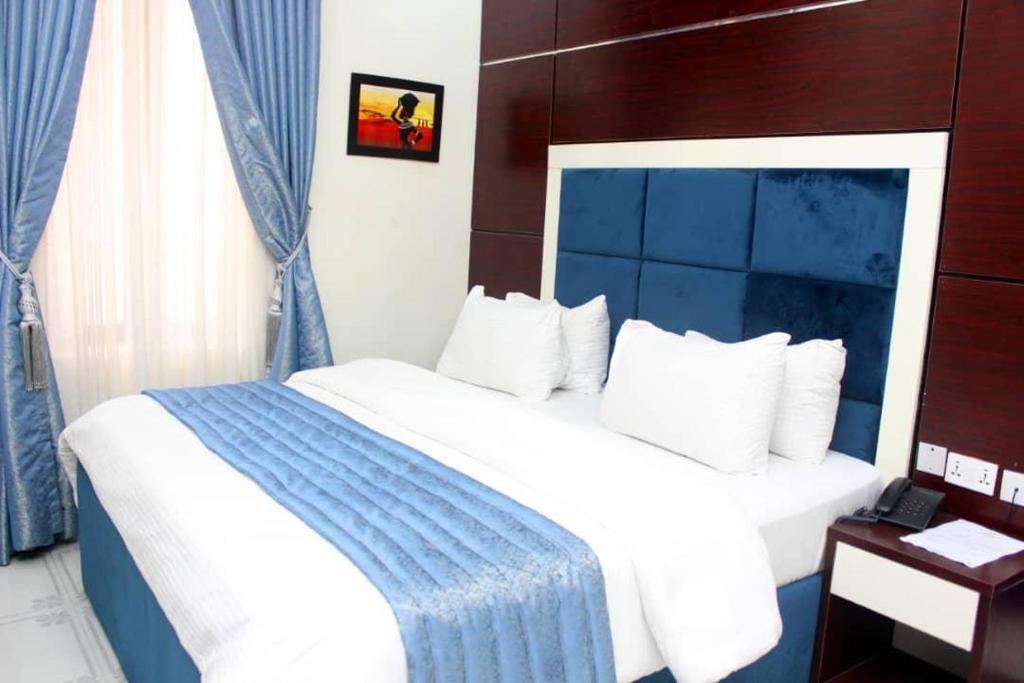 - une chambre avec un lit bleu et blanc dans l'établissement Chinbell Luxury Hotel & Suites, à Wamba