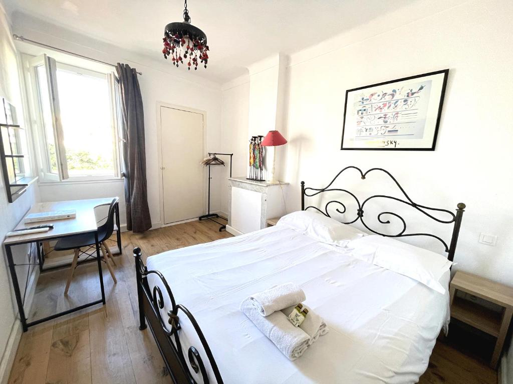 a bedroom with a large white bed and a desk at Viva Riviera - 10 Rue Commandant André in Cannes