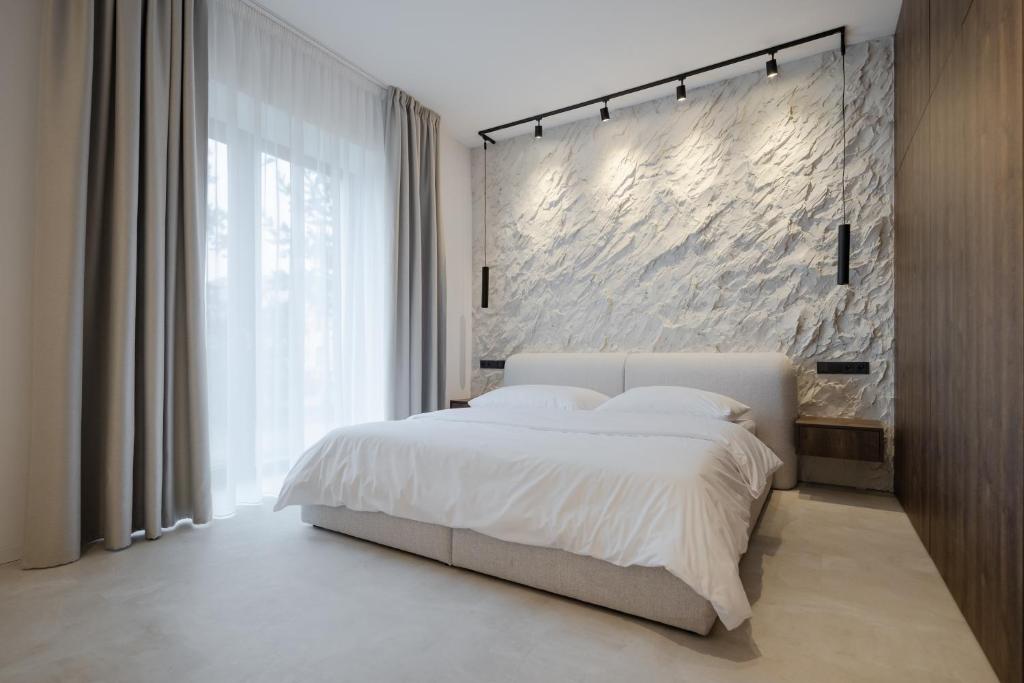 ein Schlafzimmer mit einem weißen Bett und einer Steinwand in der Unterkunft Imperial Residence - design aparthotel in city center, private parking in Banská Bystrica