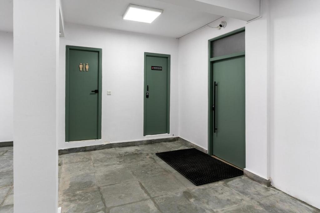 a row of three green doors in a white room at Cosy 1 Bedroom Studio with King Bed Kitchenet in Central Kathmandu with Terrace in Kathmandu