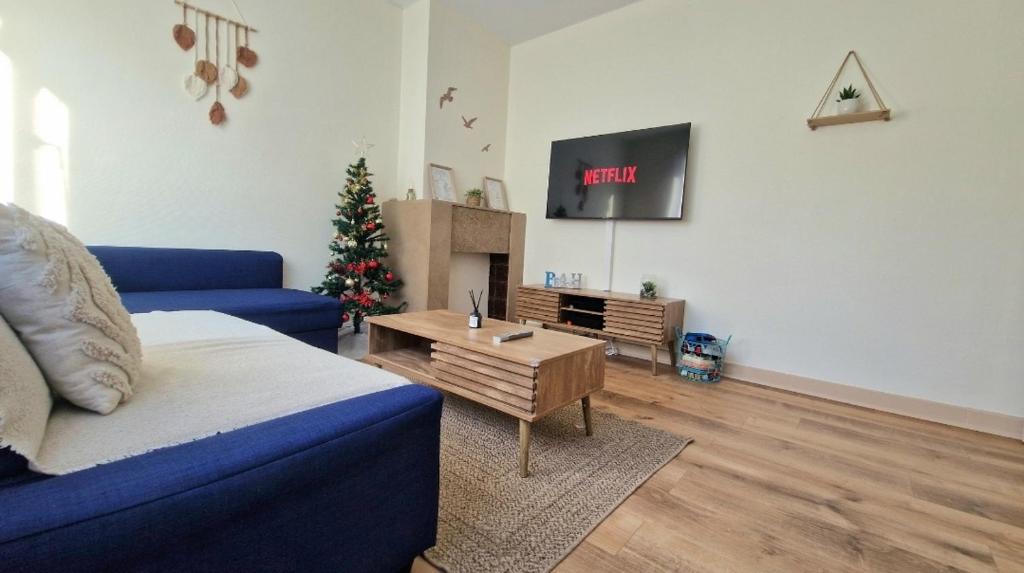 ein Wohnzimmer mit einer blauen Couch und einem Weihnachtsbaum in der Unterkunft Caprices des vagues - A 300 m de la plage et à 4 kilomètres de Nausicaa, Place de parking privée, Eau douce, Netflix, Primes Vidéo, Wifi haut débit in Le Portel