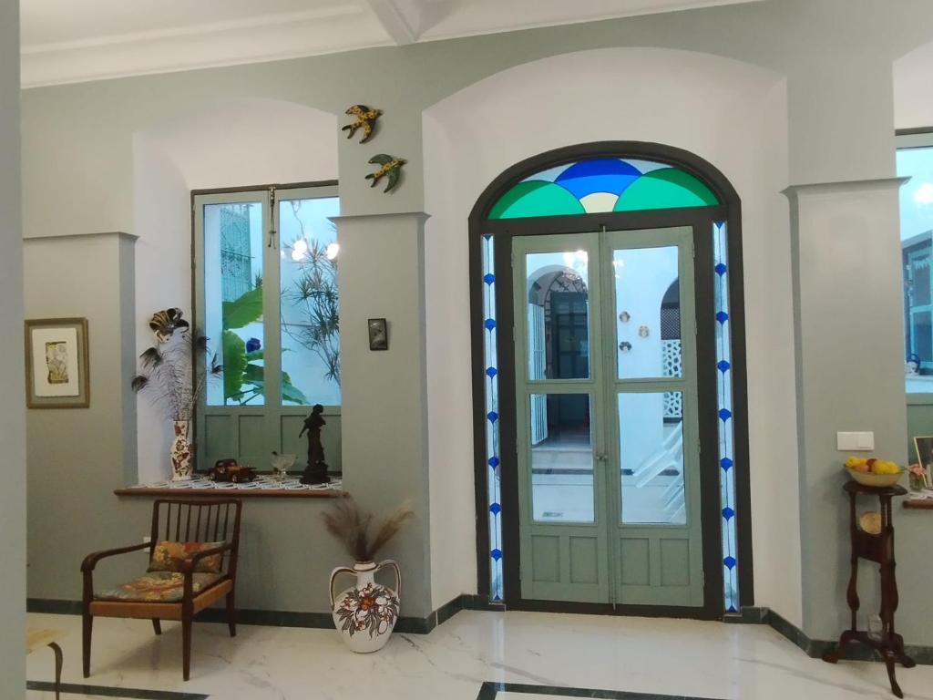 Cette chambre dispose d'une porte verte et d'une chaise. dans l'établissement CASA SEÑORIAL CON PISCINA. CASA DONNA ISABEL, à Peñaflor