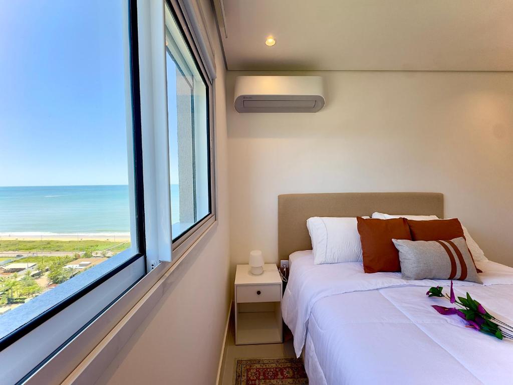 Una cama o camas en una habitación de Apartamento em Condomínio Frente-Mar com Piscinas, Jacuzzi Aquecida, Sauna, Academia, Brinquedoteca, Churrasqueira na Sacada, Cozinha Completa e Lazer de Home Club