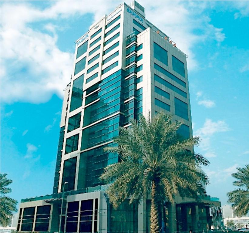 un grand bâtiment avec un palmier devant lui dans l'établissement Samaya Hotel Deira, à Dubaï