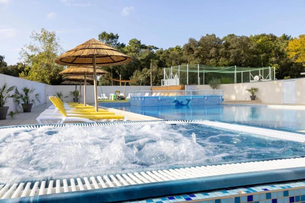 ein Schwimmbecken mit Sonnenschirm und gelben Stühlen und ein Schwimmbecken in der Unterkunft Camping 4 étoiles - Piscine - cbgcb0b in Saint-Jean-de-Monts