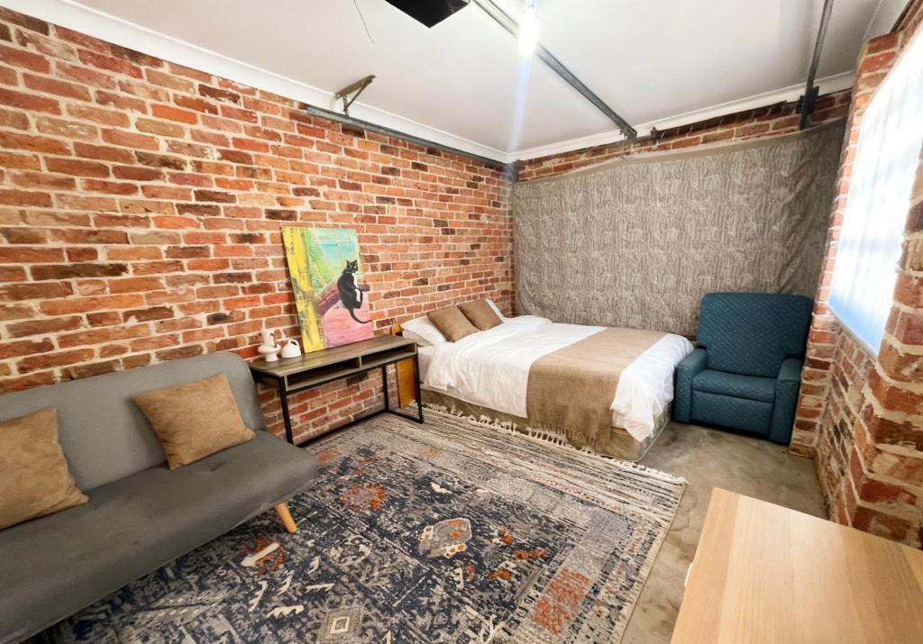 Burwood Family Guest Home في سيدني: غرفة نوم بها سرير وجدار من الطوب