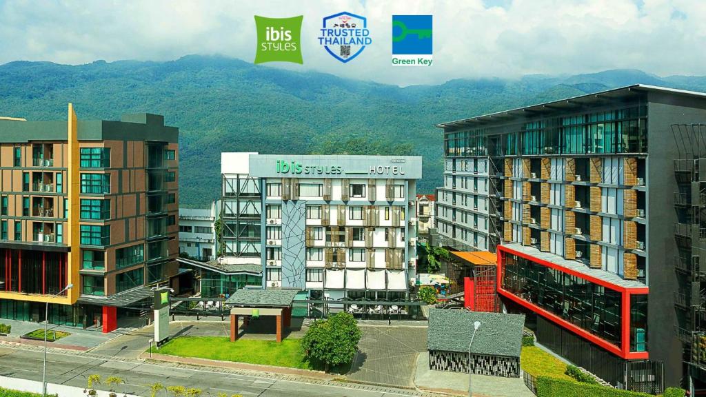 un grupo de edificios con montañas en el fondo en ibis Styles Chiang Mai, en Chiang Mai