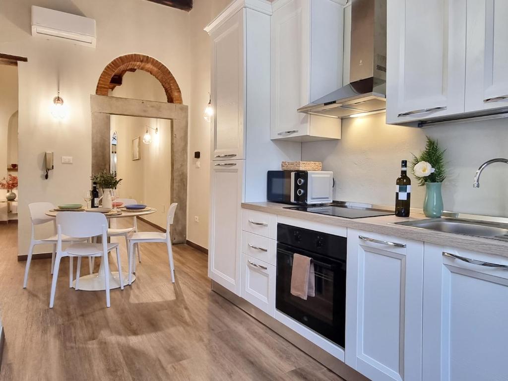 a kitchen with white cabinets and a table with chairs at "Suite del Borgo" charming flat at 30 min from Florence, 2 Smart TV in San Giovanni Valdarno