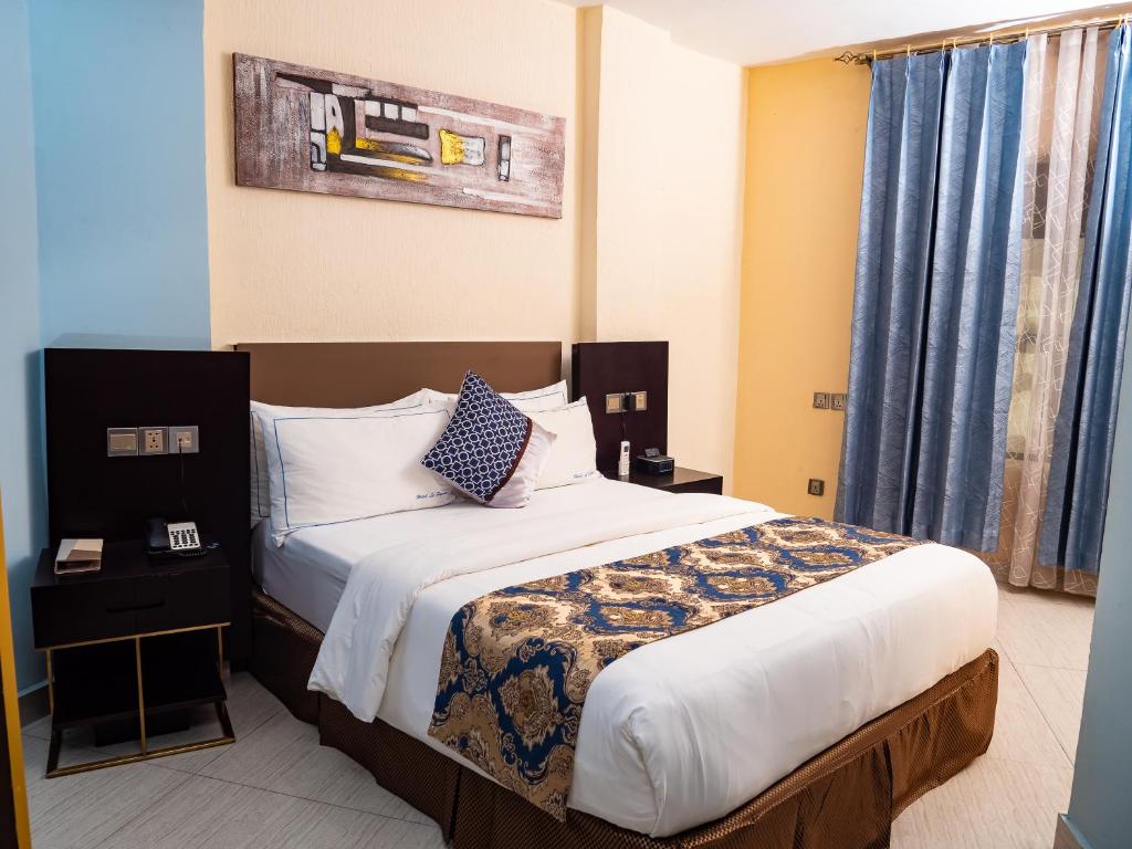 Un dormitorio con una cama grande con cortinas azules. en FOPROLUX Palace, en Douala