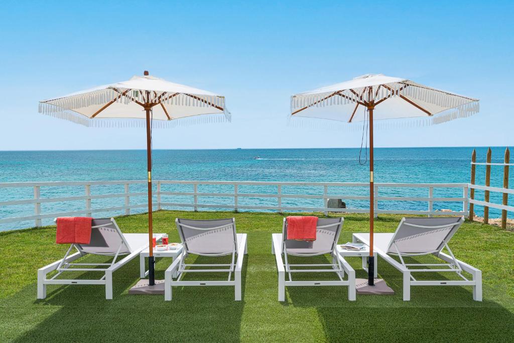 a group of chairs and umbrellas next to the ocean at Villa Hermes in Noto Marina