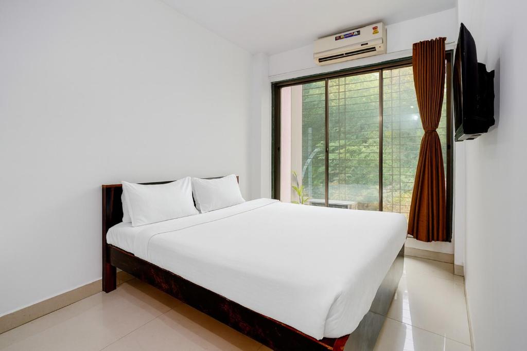 een wit bed in een kamer met een raam bij A R Residency in Navi Mumbai