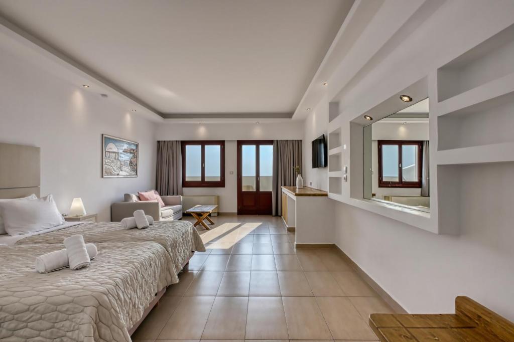 a bedroom with a large bed and a living room at Splendour Hotel and Suites in Firostefani